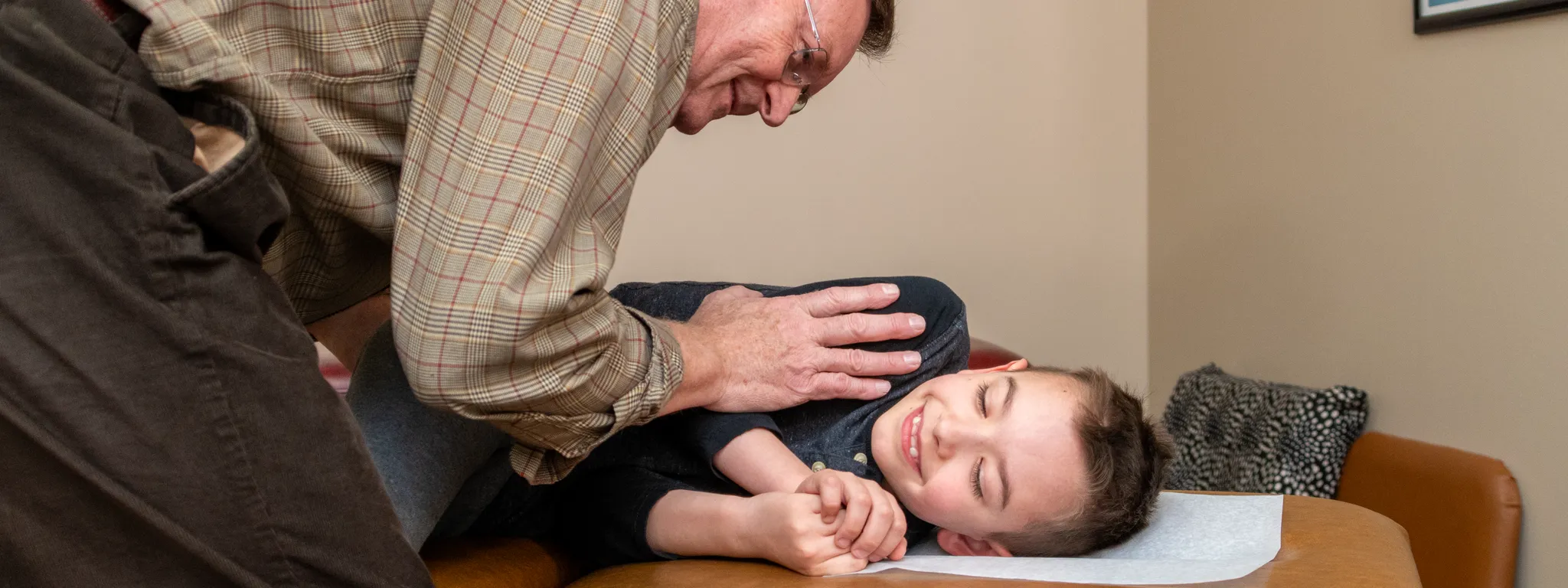 A Gentle Pediatric Adjustment, Chiropractic Care for Kids in Macomb, MI Dr. Bence gently adjusts a smiling young boy lying on the treatment table during a pediatric chiropractic visit at Bence Chiropractic Wellness Center.