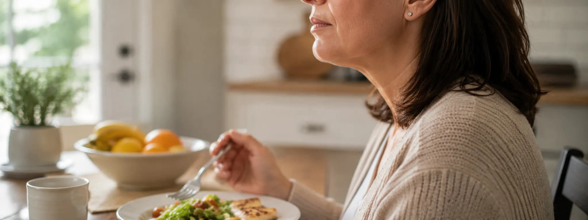 Difficulty Chewing at Mealtime, TMJD Treatment in Macomb, MI A woman pauses mid-meal at her kitchen table, one hand raised near her jaw, as if a bite of food triggered jaw discomfort.